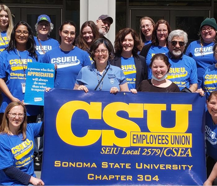 Group of CSUEU Chapter 304 members dressed in blue and yellow and holding a union banner
