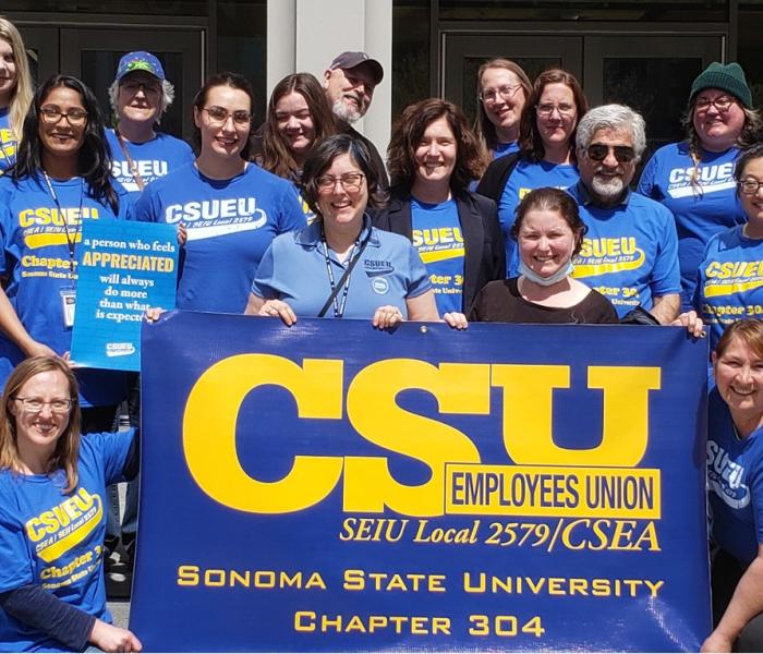 Group of CSUEU Chapter 304 members dressed in blue and yellow and holding a union banner