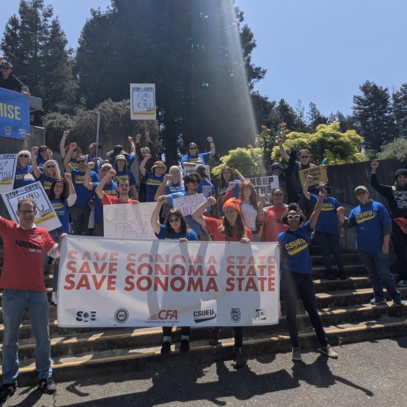 Many people standing on stairs, arms raised.  Signs state Keep the Promise, Save Sonoma State and Fund the CSU